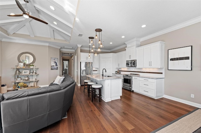 kitchen featuring a center island with sink, hanging light fixtures, light stone counters, white cabinetry, and stainless steel appliances