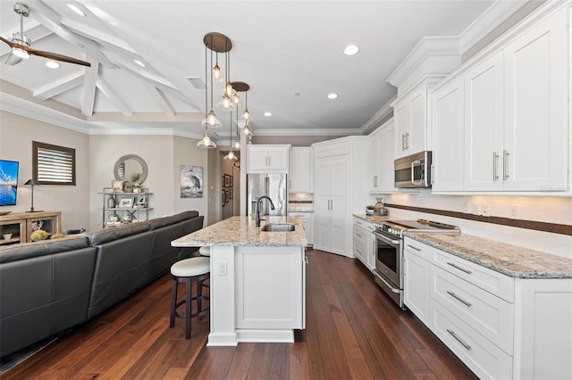 kitchen with beam ceiling, stainless steel appliances, white cabinetry, and a kitchen island with sink