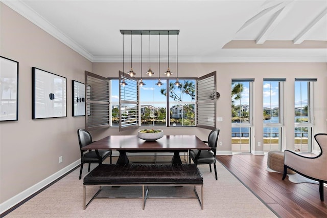 dining area featuring a healthy amount of sunlight, a water view, wood-type flooring, and crown molding