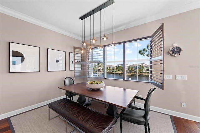 dining area featuring crown molding, a water view, and dark wood-type flooring