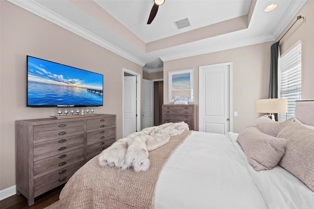 bedroom featuring hardwood / wood-style flooring, ceiling fan, crown molding, and a tray ceiling