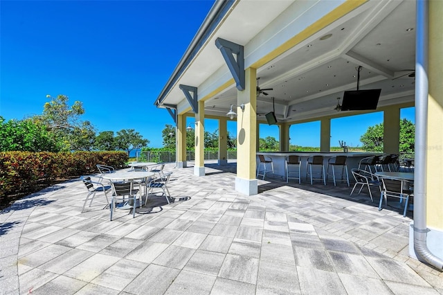 view of patio with ceiling fan and an outdoor bar