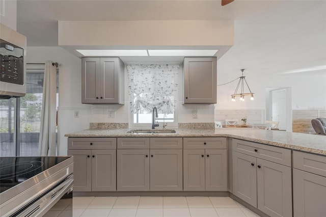 kitchen featuring gray cabinetry, pendant lighting, light stone counters, and sink