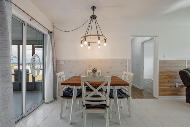 tiled dining room with a notable chandelier and wood walls