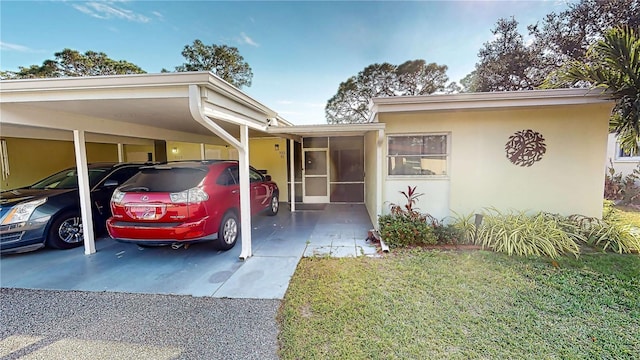 view of front of property with a carport, a sunroom, and a front lawn