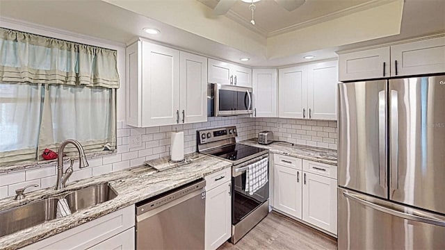 kitchen featuring white cabinets, appliances with stainless steel finishes, crown molding, and sink