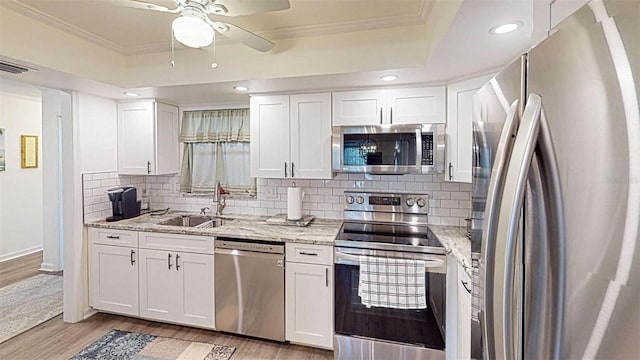 kitchen with white cabinets, a raised ceiling, sink, light hardwood / wood-style flooring, and appliances with stainless steel finishes