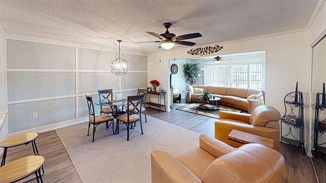 living room featuring wood-type flooring, ceiling fan with notable chandelier, a textured ceiling, and crown molding