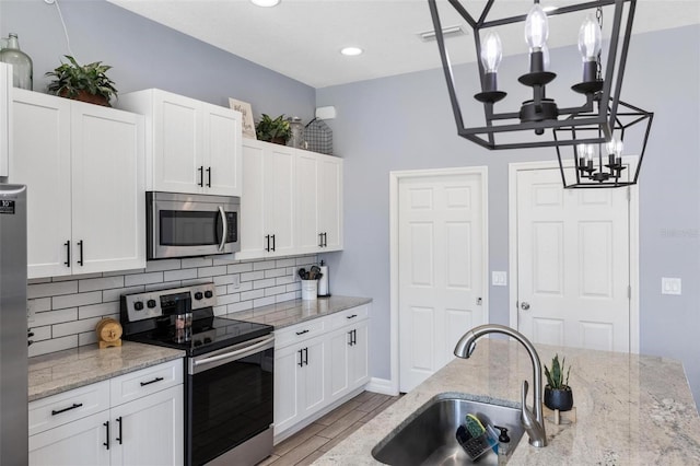 kitchen with appliances with stainless steel finishes, white cabinetry, and sink