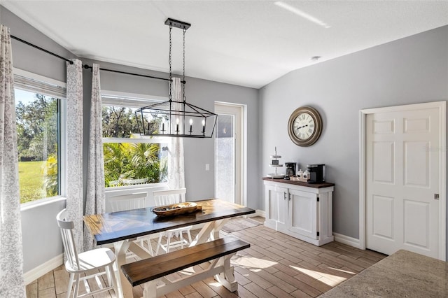 dining area with an inviting chandelier, vaulted ceiling, and plenty of natural light