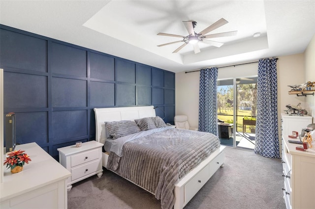 bedroom featuring carpet flooring, ceiling fan, access to outside, and a tray ceiling