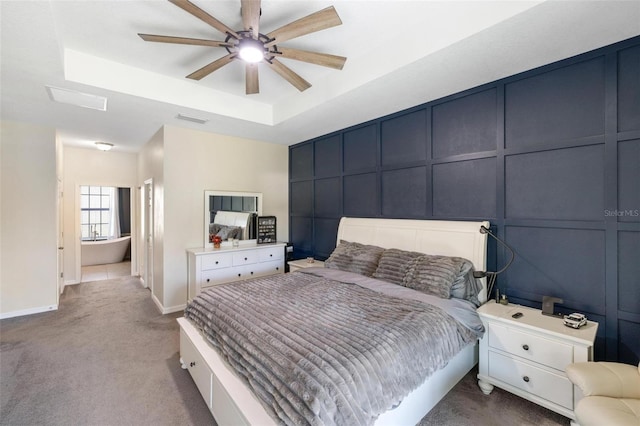 carpeted bedroom with a tray ceiling and ceiling fan