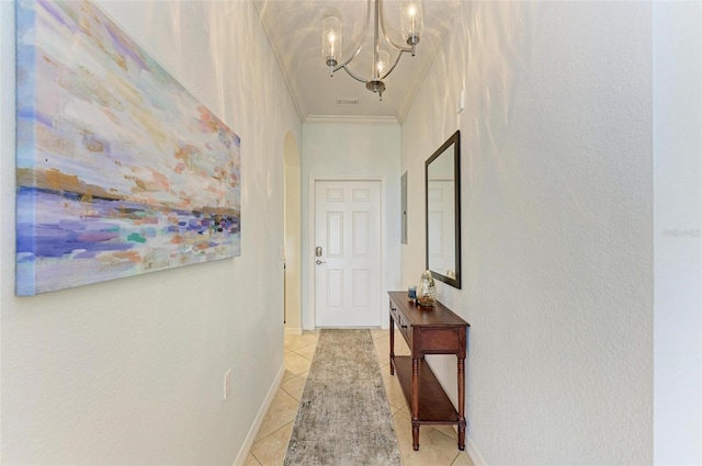 hallway with crown molding, light tile patterned flooring, and an inviting chandelier