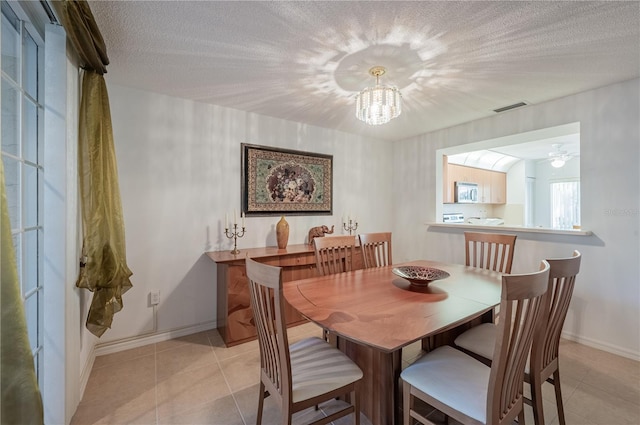 tiled dining room featuring a textured ceiling and ceiling fan with notable chandelier