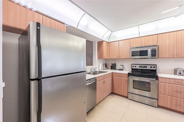 kitchen with sink, light brown cabinets, light tile patterned floors, and appliances with stainless steel finishes