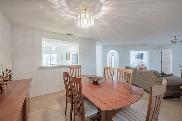 dining space featuring a textured ceiling, ceiling fan with notable chandelier, and light tile patterned floors