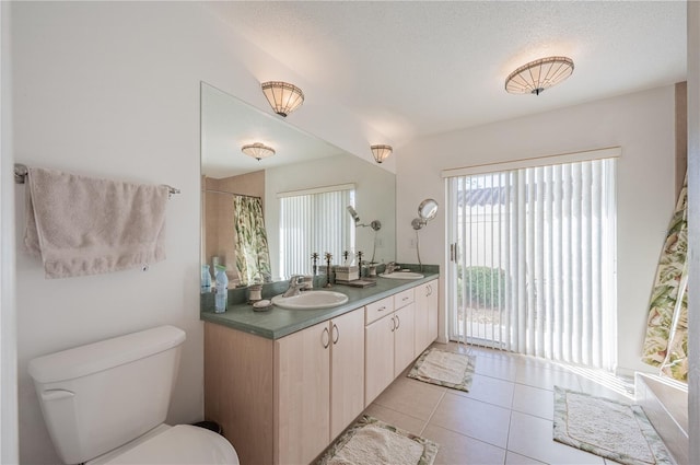 bathroom with a textured ceiling, vanity, tile patterned floors, and toilet