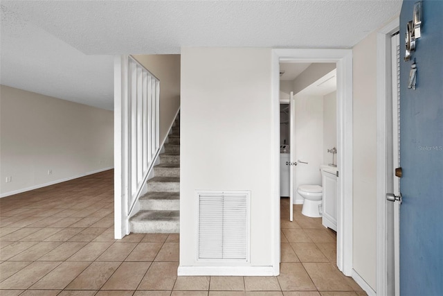 stairs featuring tile patterned flooring and a textured ceiling