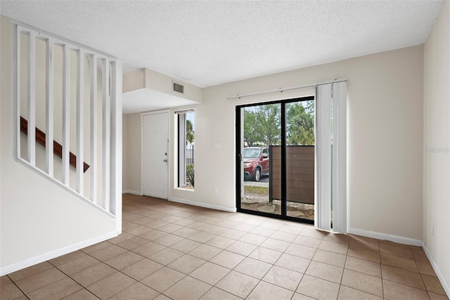 spare room with a textured ceiling and light tile patterned flooring