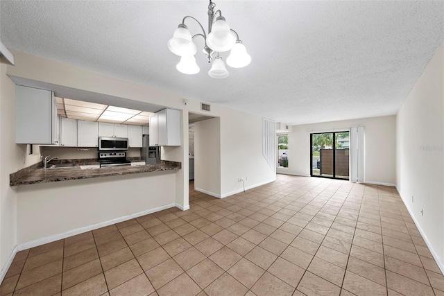 kitchen featuring pendant lighting, stove, white cabinets, kitchen peninsula, and a chandelier