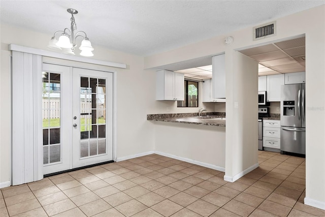 kitchen featuring a notable chandelier, white cabinets, light tile patterned floors, decorative light fixtures, and stainless steel appliances