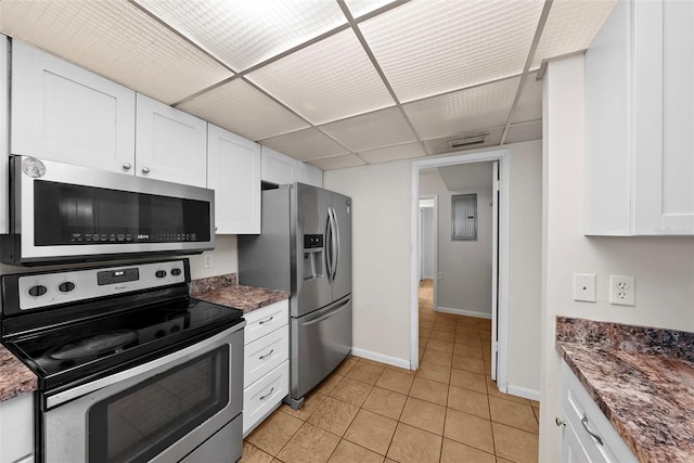 kitchen with a paneled ceiling, light tile patterned flooring, white cabinetry, and appliances with stainless steel finishes