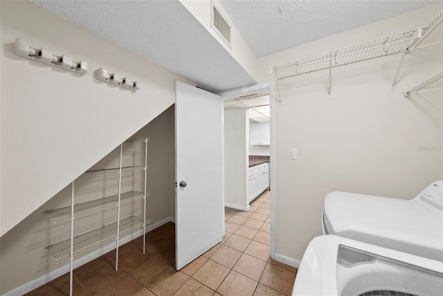 washroom with light tile patterned flooring, a textured ceiling, and washing machine and clothes dryer