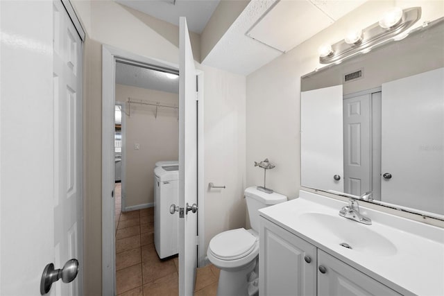 bathroom featuring washer and dryer, vanity, toilet, and tile patterned flooring