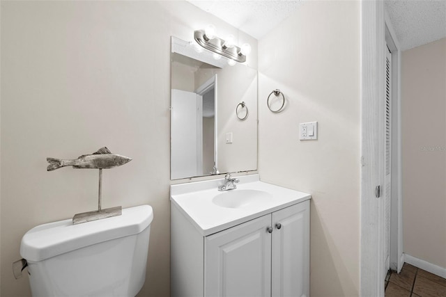 bathroom with tile patterned floors, vanity, a textured ceiling, and toilet