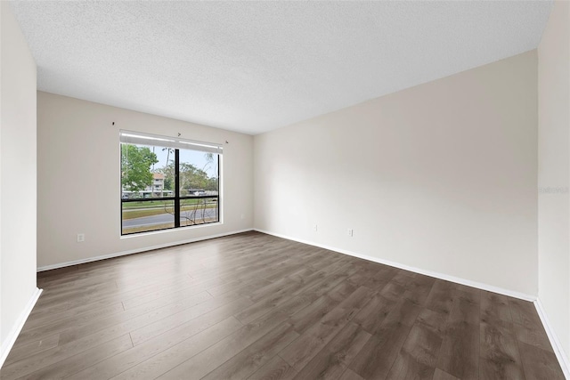 spare room featuring a textured ceiling and dark wood-type flooring