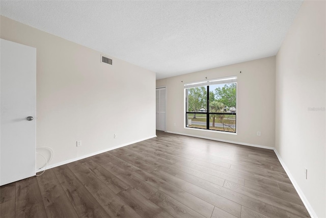 unfurnished room with dark wood-type flooring and a textured ceiling