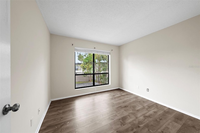 spare room featuring wood-type flooring and a textured ceiling