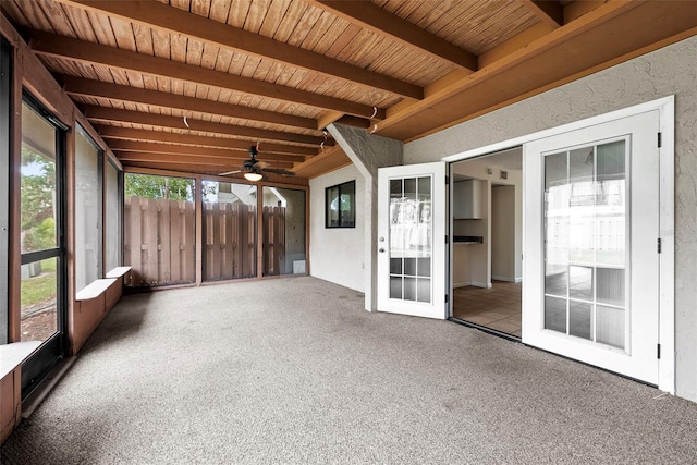 unfurnished sunroom with beamed ceiling, ceiling fan, wood ceiling, and french doors