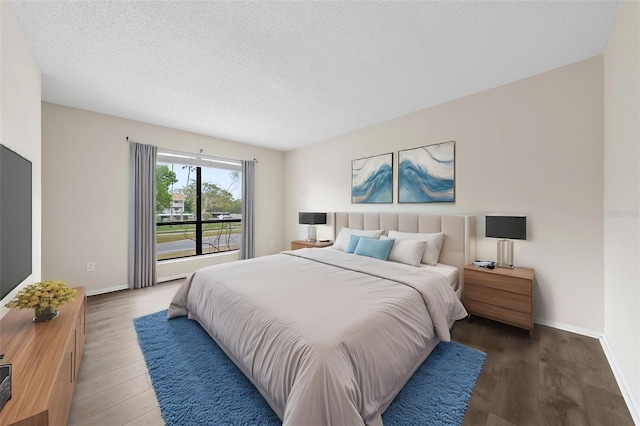 bedroom with a textured ceiling, baseboards, and wood finished floors