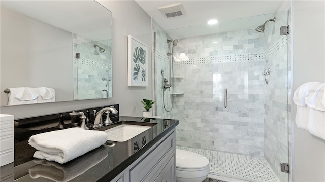 bathroom featuring visible vents, a shower stall, toilet, and vanity