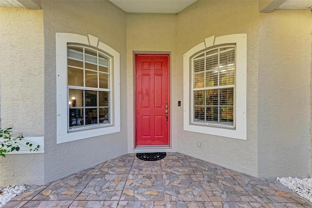 doorway to property featuring covered porch and stucco siding