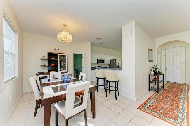 dining area with arched walkways, light tile patterned floors, visible vents, a chandelier, and baseboards