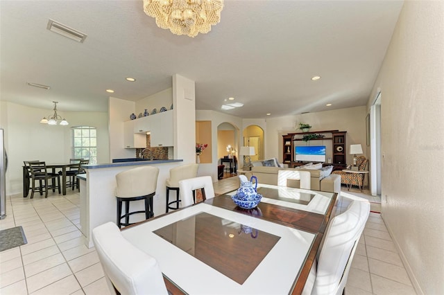 dining room with a chandelier, light tile patterned floors, arched walkways, recessed lighting, and visible vents