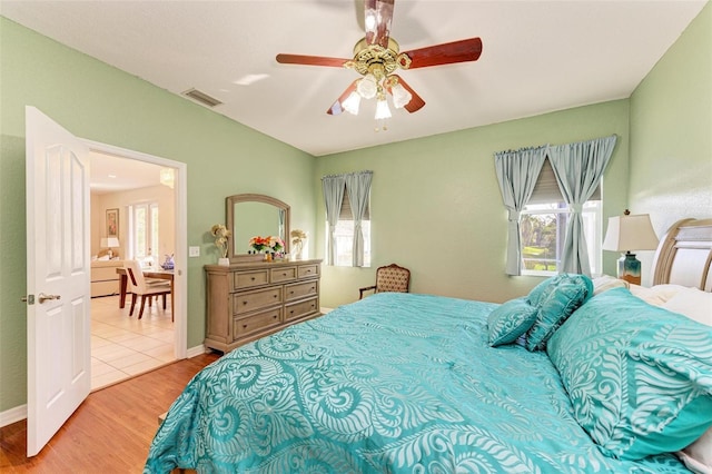 bedroom with ceiling fan, multiple windows, visible vents, and wood finished floors