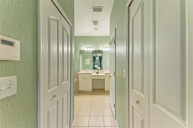 bathroom featuring a textured ceiling, a textured wall, vanity, visible vents, and tile patterned floors