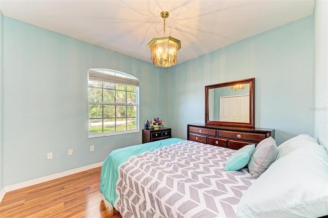 bedroom featuring an inviting chandelier, baseboards, and wood finished floors