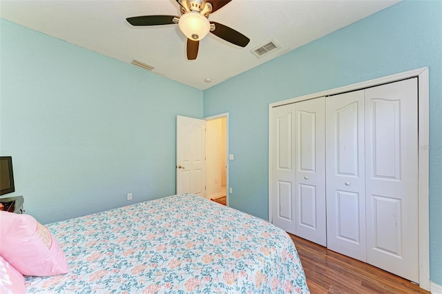 bedroom with ceiling fan, a closet, wood finished floors, and visible vents