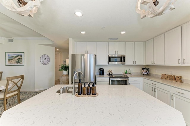 kitchen featuring appliances with stainless steel finishes, light stone counters, crown molding, sink, and white cabinetry