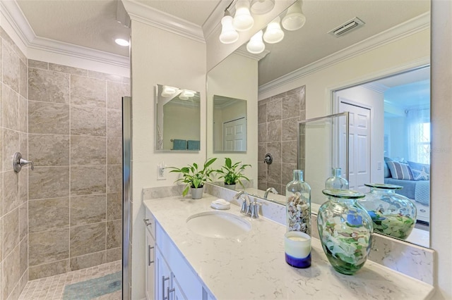 bathroom with vanity, crown molding, and tiled shower