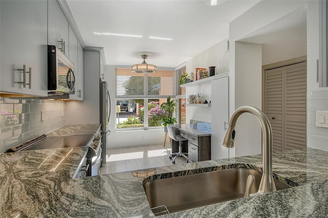 kitchen featuring backsplash, dark stone countertops, sink, and appliances with stainless steel finishes