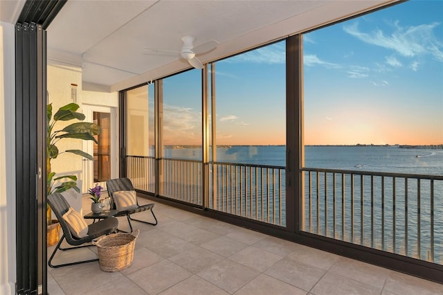 sunroom / solarium featuring ceiling fan and a water view