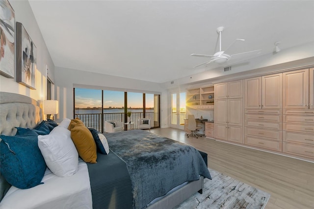 bedroom featuring access to exterior, built in desk, light hardwood / wood-style floors, and ceiling fan