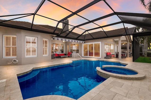 pool at dusk with a lanai, a patio area, and an in ground hot tub