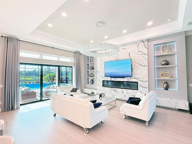 5305 Brookgrove Dr, Sarasota, FL 34238 - living room featuring a tray ceiling, built in shelves, wood finished floors, and a high end fireplace