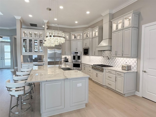 5305 Brookgrove Dr, Sarasota, FL 34238 - kitchen featuring a sink, built in appliances, light wood-type flooring, decorative backsplash, and a kitchen island with sink